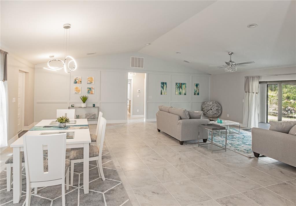 An open-concept living and dining area features light gray walls, tile flooring, and modern furniture — 13349 MENORAH DRIVE, PUNTA GORDA, FL