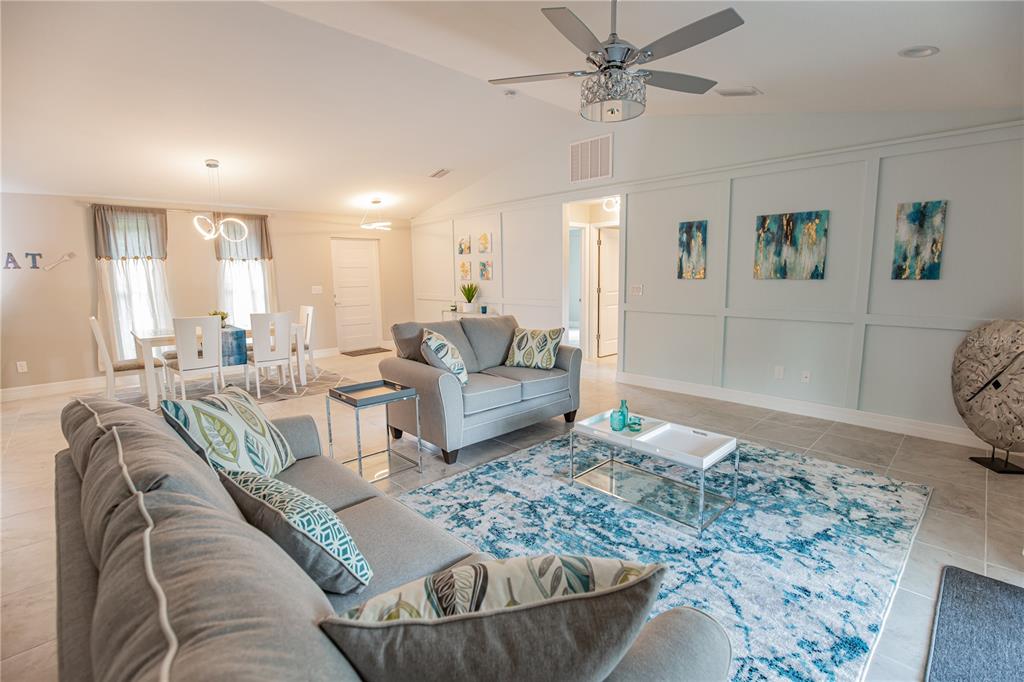 A living room with gray sofas, a blue patterned rug, and a dining area — 13349 MENORAH DRIVE, PUNTA GORDA, FL