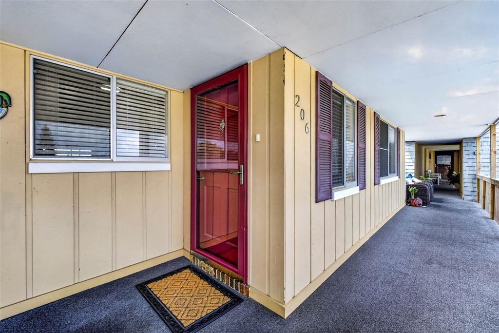 A yellow exterior wall with a red storm door and address number 206 — 1008 APOLLO BEACH BOULEVARD UNIT 206, APOLLO BEACH, FL