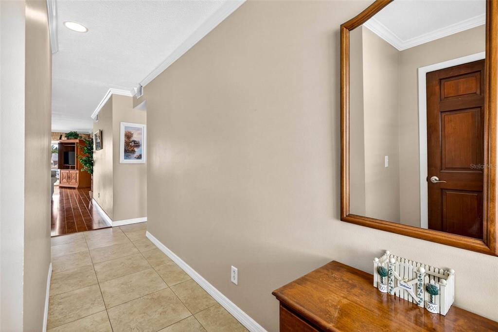 A hallway with tile flooring leads toward a living area, featuring a mirror and console — 1008 APOLLO BEACH BOULEVARD UNIT 206, APOLLO BEACH, FL