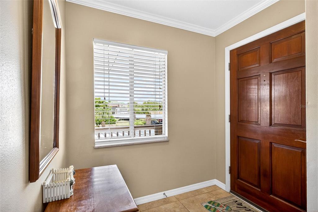 An entryway features a wooden door, a window with blinds, a mirror, and a console table — 1008 APOLLO BEACH BOULEVARD UNIT 206, APOLLO BEACH, FL