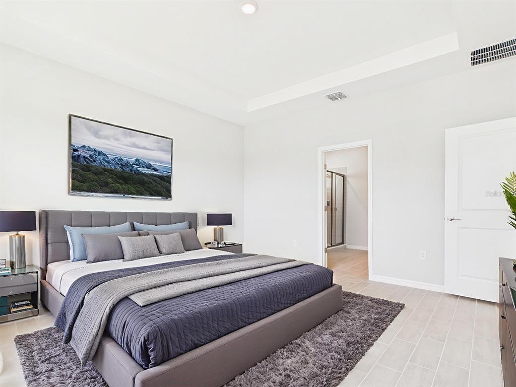 A modern bedroom features a gray upholstered bed, a shag rug, and an attached bathroom — 8419 N INCA WAY, DUNNELLON, FL