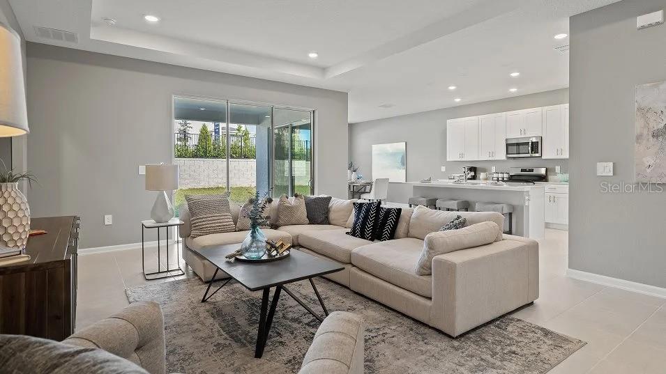 A modern kitchen features white cabinetry, a large quartz island, and three gray bar stools — 1801 RIDER RAIN LANE, APOPKA, FL