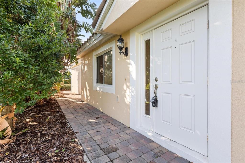 A paved walkway leads to a white front door with a sidelight and lockbox — 12223 PESCARA LANE, ORLANDO, FL