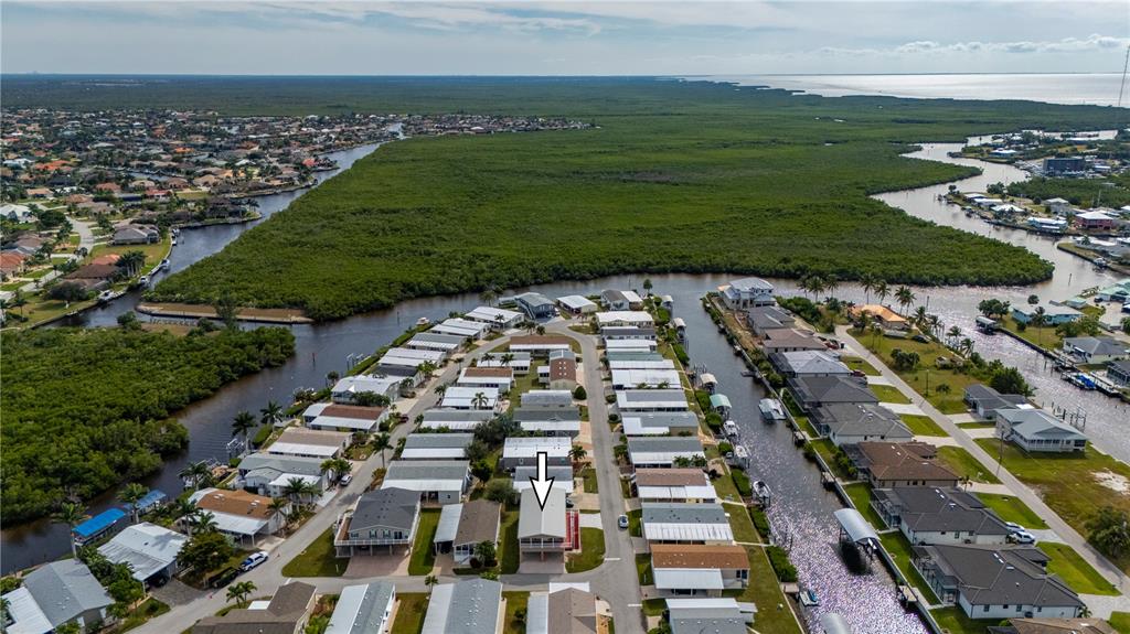 An aerial view shows a residential neighborhood with a marked house near a canal — 67 WINDMILL BOULEVARD, PUNTA GORDA, FL