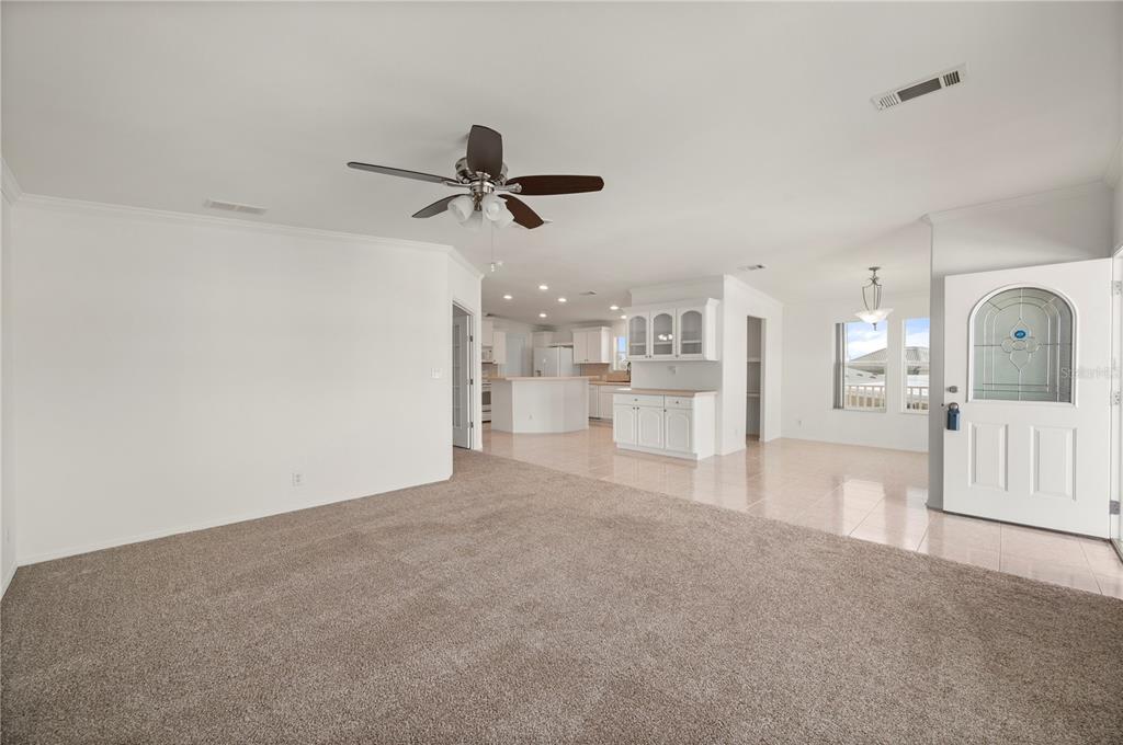 A spacious living room with carpeted flooring transitions into a tiled kitchen and dining area — 67 WINDMILL BOULEVARD, PUNTA GORDA, FL