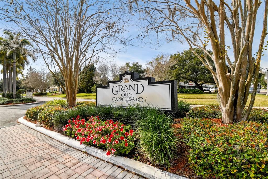 A sign for The Grand at Olde Carrollwood stands in a landscaped garden bed — 10314 CARROLLWOOD COURT UNIT 56, TAMPA, FL