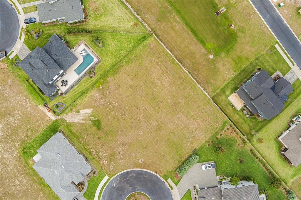 An aerial view shows a vacant residential lot surrounded by several houses and a cul-de-sac — 200 CALADONIA COURT, LAKE ALFRED, FL