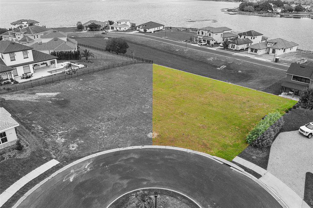An aerial view shows a vacant, grass-covered residential lot highlighted in green next to a cul-de-sac — 200 CALADONIA COURT, LAKE ALFRED, FL