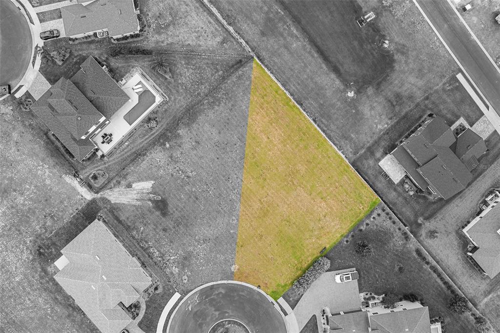 An aerial view shows a vacant, triangular-shaped residential lot highlighted in yellow — 200 CALADONIA COURT, LAKE ALFRED, FL