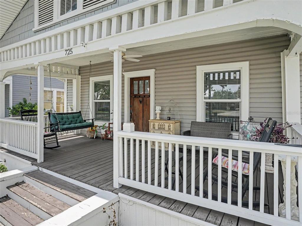 A covered front porch features a wooden swing, rocking chairs, and a wooden front door — 725 MABBETTE STREET, KISSIMMEE, FL