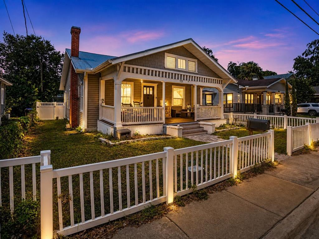 A gray bungalow with a front porch, brick chimney, and white picket fence — 725 MABBETTE STREET, KISSIMMEE, FL