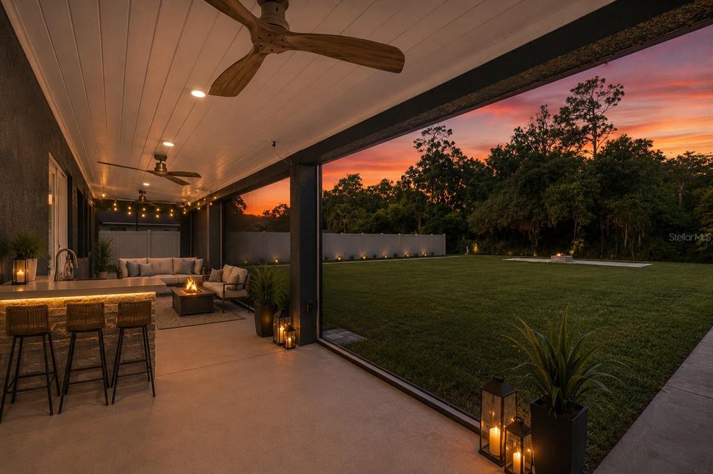 A covered patio features a bar, outdoor seating, and a view of a grassy backyard — 1330 S SHORE DRIVE, ST CLOUD, FL