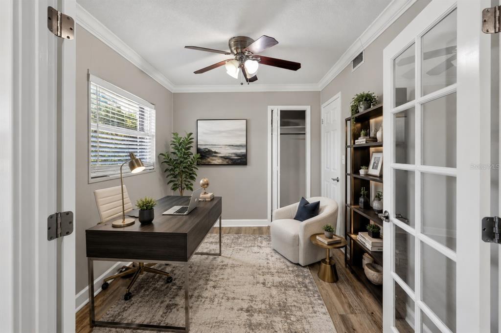 A home office features a dark wood desk, a cream armchair, and a tall bookshelf — 1330 S SHORE DRIVE, ST CLOUD, FL