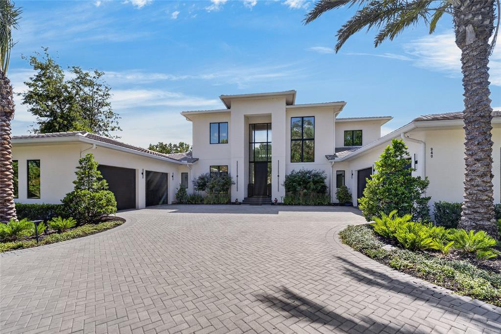 A two-story modern house with a paved driveway, multiple garages, and palm trees — TBD SE 12 CIRCLE, OCALA, FL