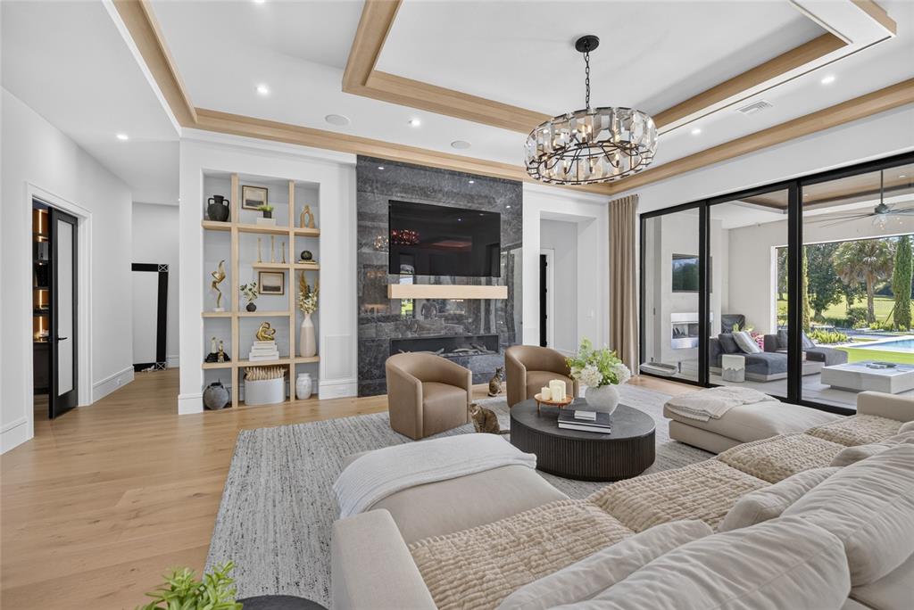 A modern living room features a dark stone fireplace, light wood flooring, and large sliding doors — TBD SE 12 CIRCLE, OCALA, FL