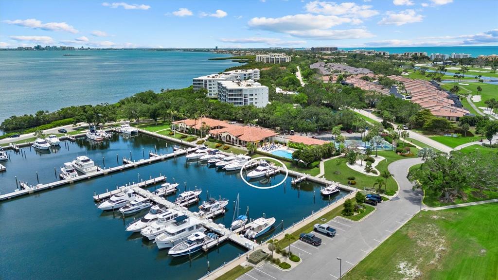An aerial view shows a marina with multiple boats docked near a coastal residential complex — 2600 HARBOURSIDE DRIVE UNIT H06, LONGBOAT KEY, FL
