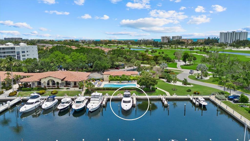 An aerial view shows a marina with several yachts docked in front of a clubhouse — 2600 HARBOURSIDE DRIVE UNIT H06, LONGBOAT KEY, FL