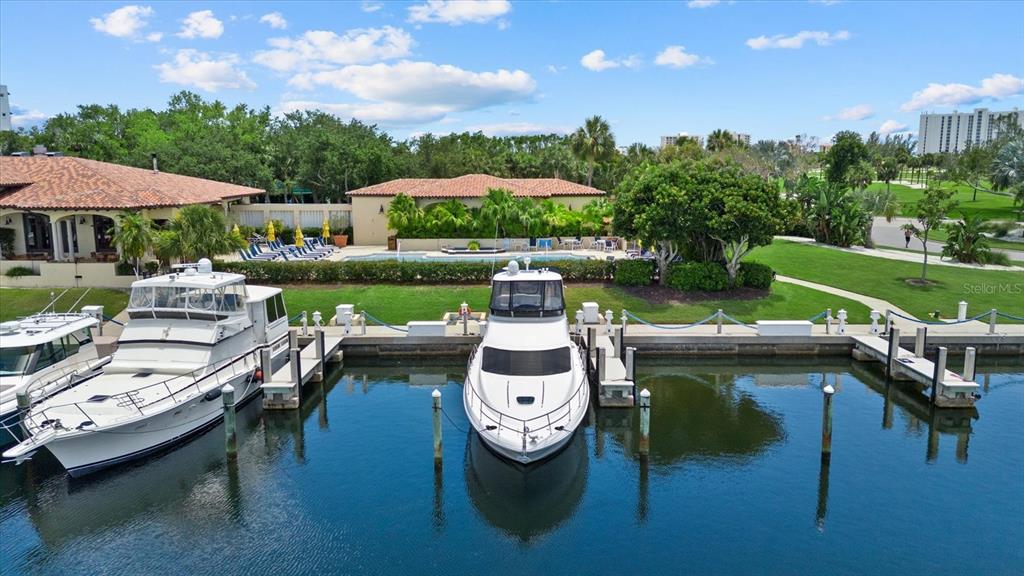 Two yachts are docked in a canal in front of a building with a pool — 2600 HARBOURSIDE DRIVE UNIT H06, LONGBOAT KEY, FL
