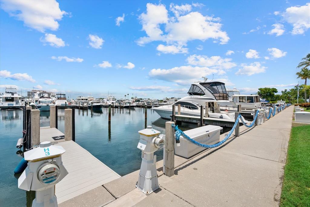 A concrete dock features utility pedestals and blue ropes alongside a marina with docked boats — 2600 HARBOURSIDE DRIVE UNIT H06, LONGBOAT KEY, FL