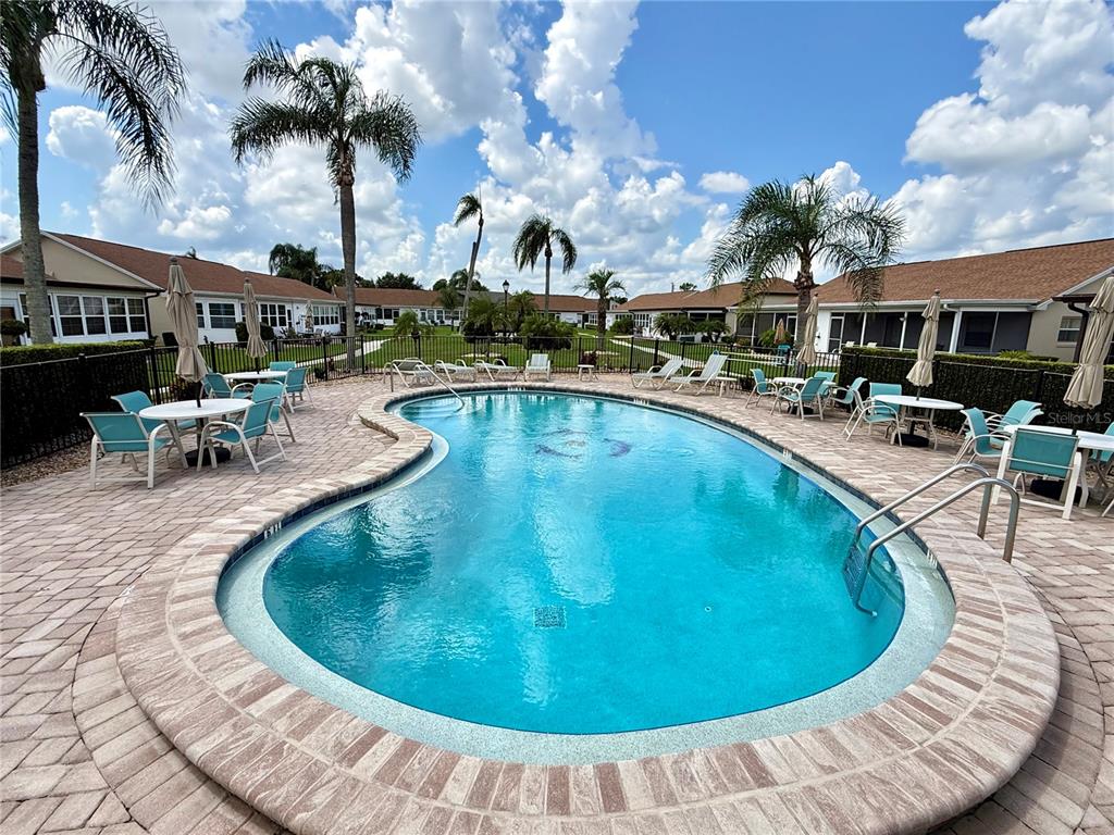 An outdoor swimming pool with a brick paver deck surrounded by palm trees and houses — 4827 CADAGUA DRIVE, SEBRING, FL