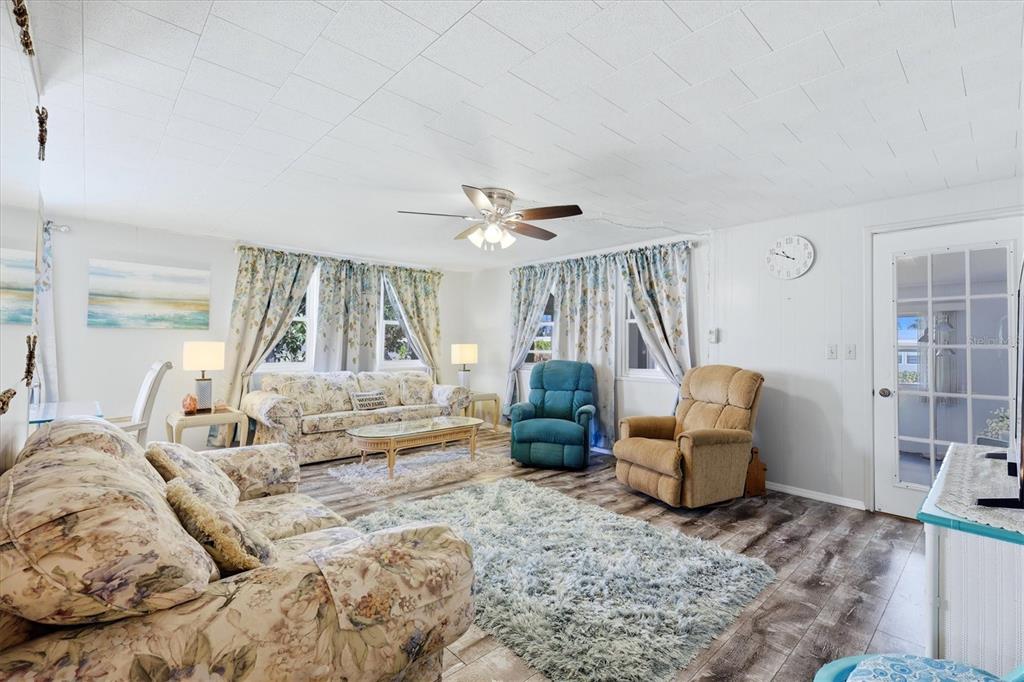 A living room features floral sofas, two recliners, a shaggy rug, and wood-look flooring — 1003 44TH AVENUE DRIVE E, ELLENTON, FL