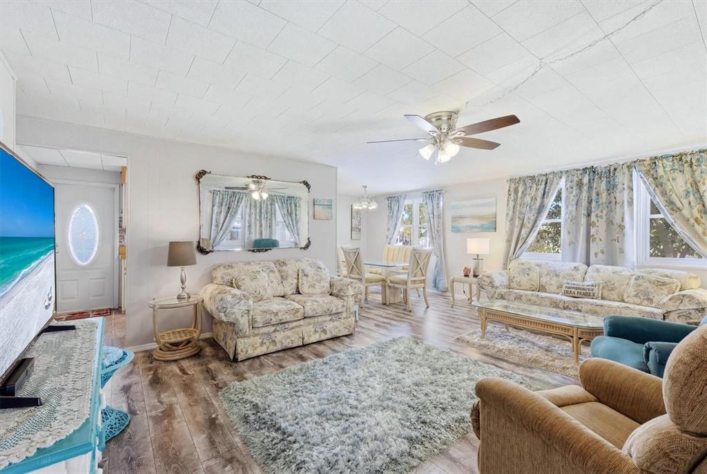 A living room with floral sofas, a shag rug, wood-look flooring, and a ceiling fan — 1003 44TH AVENUE DRIVE E, ELLENTON, FL