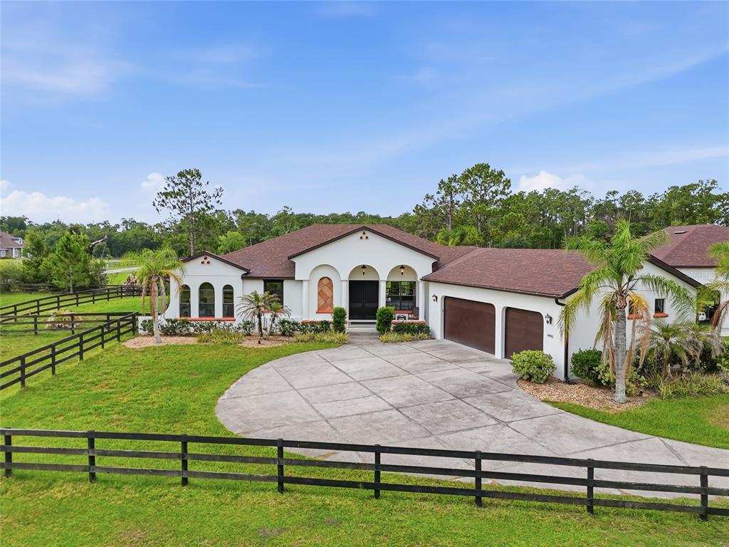 A single-story white stucco house with a brown roof and a circular concrete driveway — 4460 RUNWAY LANE, ST CLOUD, FL