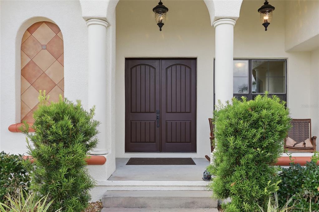 A front entrance with double brown doors, two white columns, and two green shrubs — 4460 RUNWAY LANE, ST CLOUD, FL