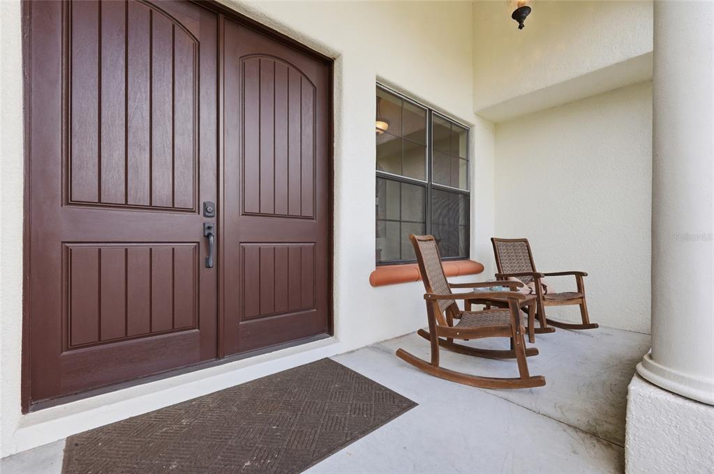 A covered porch features double brown doors, a window, and two wooden rocking chairs — 4460 RUNWAY LANE, ST CLOUD, FL