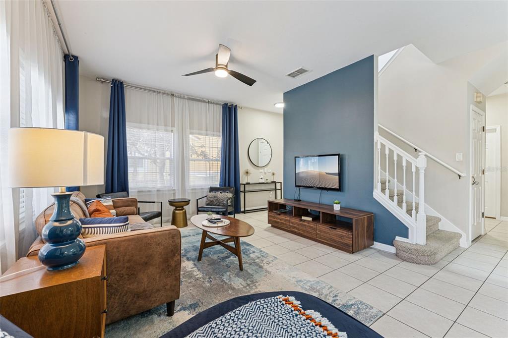 A living room features a blue accent wall, a brown sofa, and a staircase — 8572 BAY LILLY LOOP, KISSIMMEE, FL