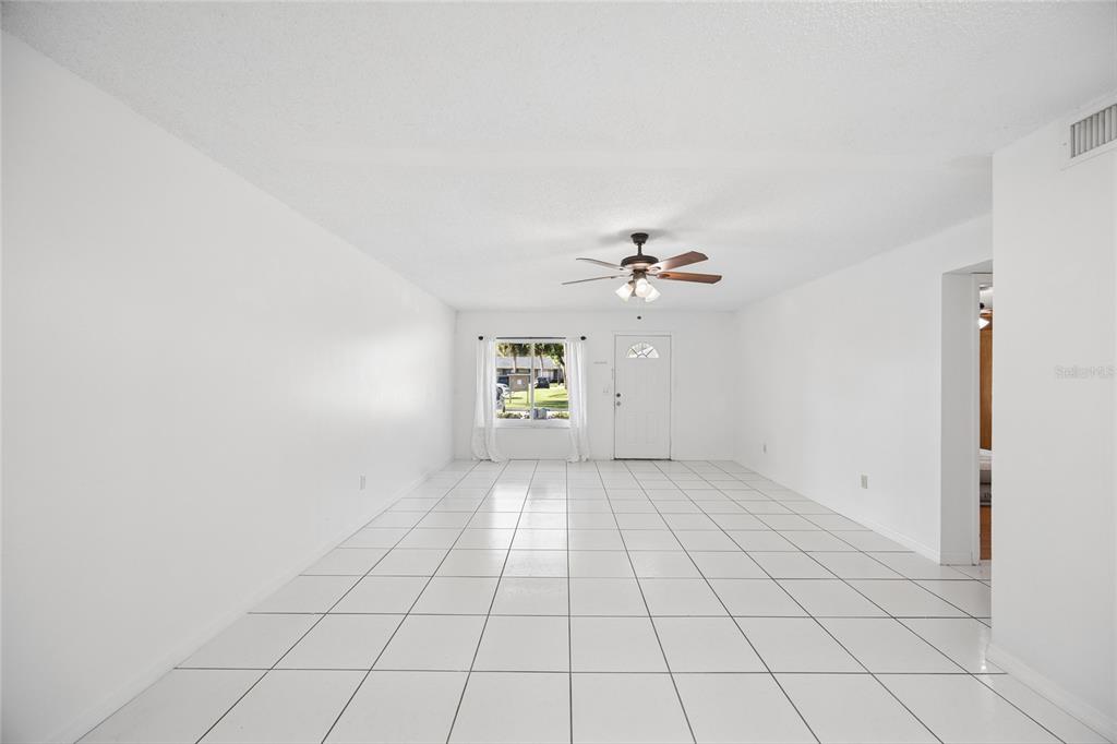A bright, empty living room features white walls, white tile flooring, and a ceiling fan — 725 NORTHLAKE BOULEVARD UNIT 10, ALTAMONTE SPRINGS, FL