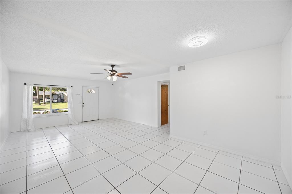 A bright, empty living room features white walls, white tile flooring, and a ceiling fan — 725 NORTHLAKE BOULEVARD UNIT 10, ALTAMONTE SPRINGS, FL