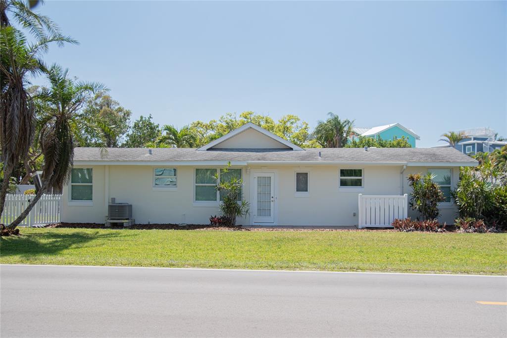 A patio with white outdoor furniture sits outside a house with a light-colored exterior — 117 79TH STREET, HOLMES BEACH, FL