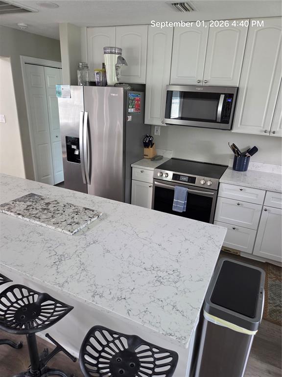 A kitchen features white cabinets, stainless steel appliances, and a large white quartz island — 117 79TH STREET, HOLMES BEACH, FL