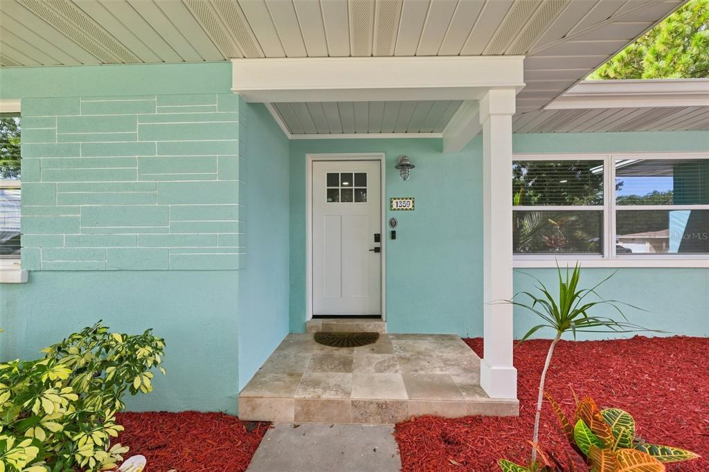 The exterior view shows a turquoise house with a white front door and tiled porch — 1359 HOWARD STREET, CLEARWATER, FL