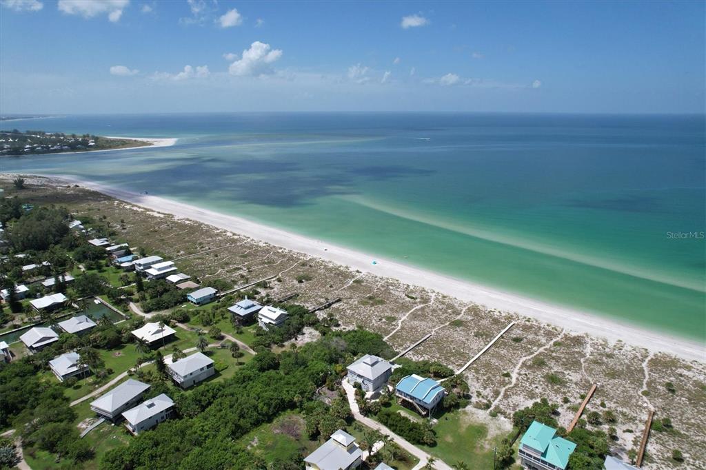 An aerial view shows beach houses nestled among trees along a sandy coastline and ocean — 9478 ALBORADO ROAD, PLACIDA, FL
