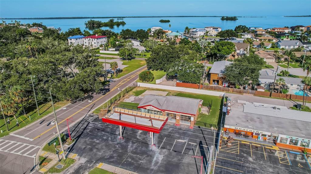 An aerial view shows a commercial building with a red-roofed canopy and adjacent parking lot — 2000 BAYSHORE BOULEVARD, DUNEDIN, FL