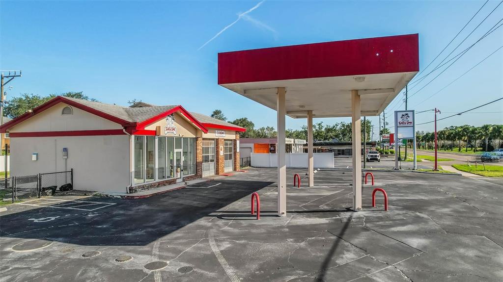 A commercial building with a red-trimmed roof and a detached fuel canopy stands outdoors — 2000 BAYSHORE BOULEVARD, DUNEDIN, FL