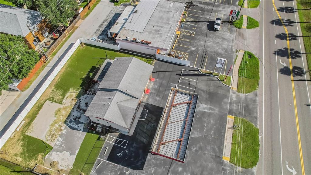An aerial view shows a commercial building with a parking lot and a metal frame structure — 2000 BAYSHORE BOULEVARD, DUNEDIN, FL