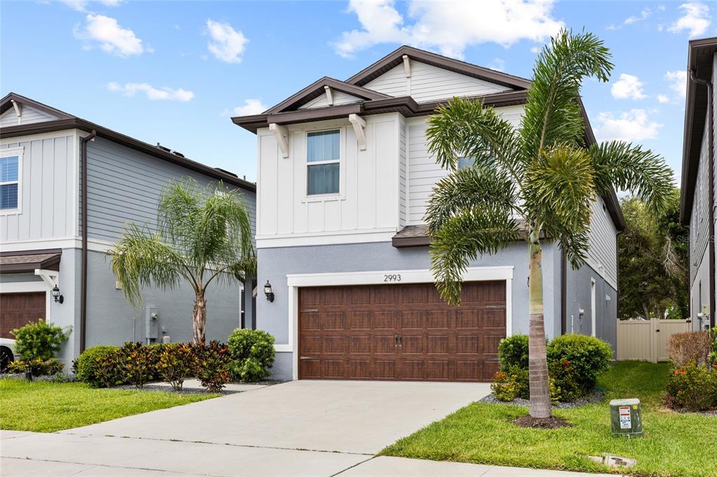 A two-story house with a brown garage door, light gray siding, and a palm tree — 2993 PIER POINTE LANE, CLEARWATER, FL