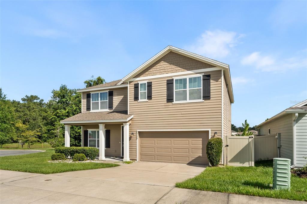 A two-story suburban house with tan siding, a two-car garage, and a covered front porch — 8008 SW 62ND COURT, GAINESVILLE, FL