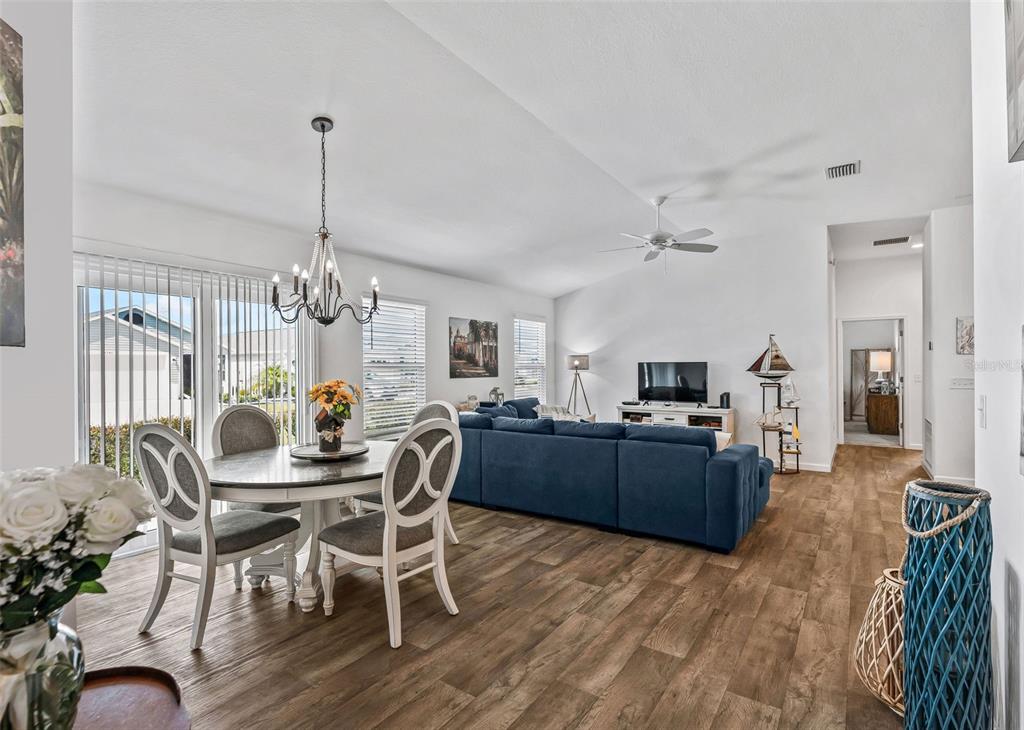 A dining area with a white table and chairs sits beside a blue sectional sofa — 3250 SHERFINSKI AVENUE, THE VILLAGES, FL