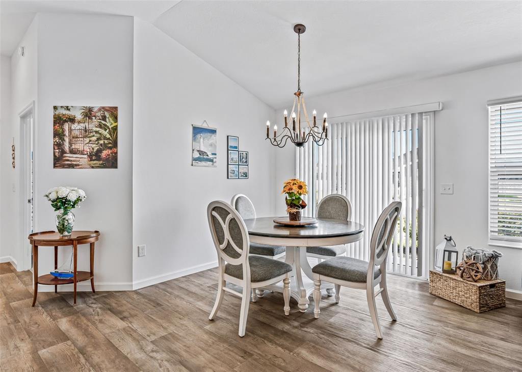A dining area features a round table, four chairs, a chandelier, and wood-look flooring — 3250 SHERFINSKI AVENUE, THE VILLAGES, FL