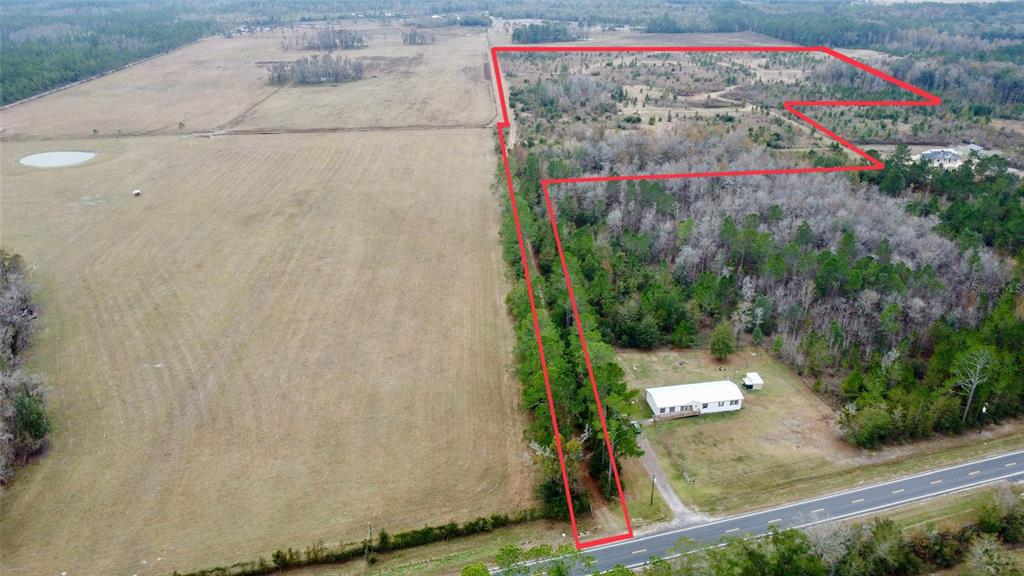 An aerial view shows a single-story house situated on a large, wooded rural lot — TBD CR 235, BROOKER, FL