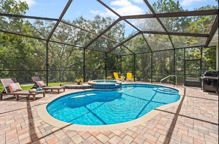 A screened-in patio features a swimming pool with an attached spa and brick paver decking — 1 COLUBRINA COURT, HOMOSASSA, FL