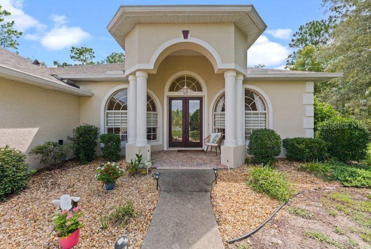 The exterior of a beige house features a covered entryway with white columns and double doors — 1 COLUBRINA COURT, HOMOSASSA, FL