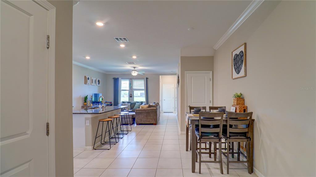 An open-concept living area features a kitchen island with bar stools and a dining set — 31632 BLUE PASSING LOOP, WESLEY CHAPEL, FL