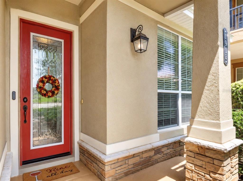 A red front door with a glass insert and wreath sits on a covered porch — 1925 APPALACHEE, TAVARES, FL
