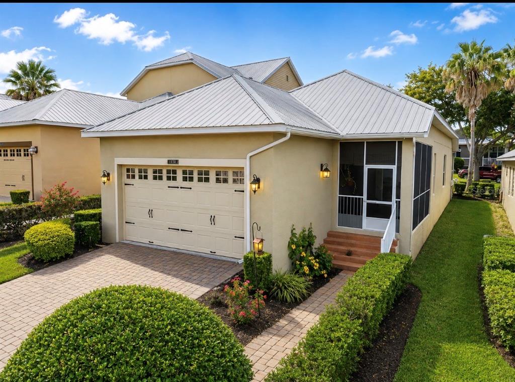 A beige single-story house with a metal roof, a two-car garage, and a screened entryway — 1925 APPALACHEE, TAVARES, FL